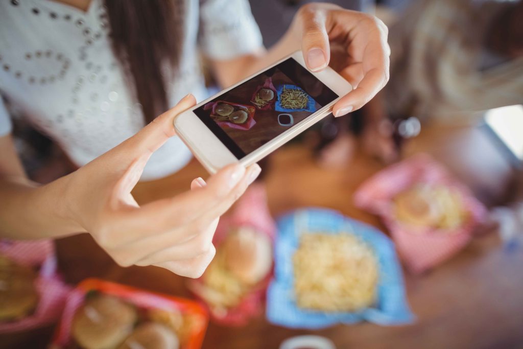 happy-digital-software-app-development-company-woman photographing food through mobile in restaur 2021 08 28 16 44 47 utc 1
