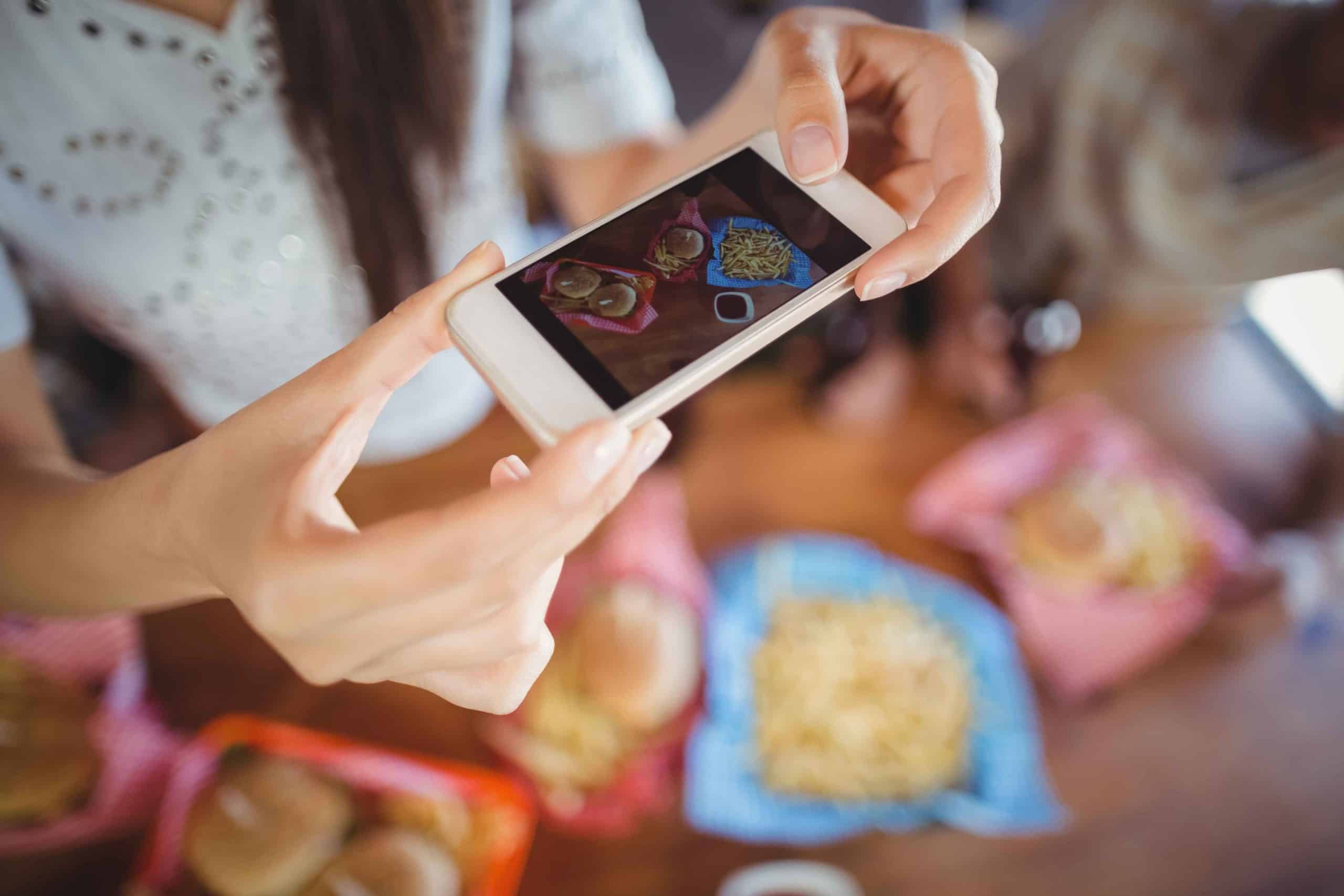 happy-digital-software-app-development-company-woman photographing food through mobile in restaur 2021 08 28 16 44 47 utc 1 scaled